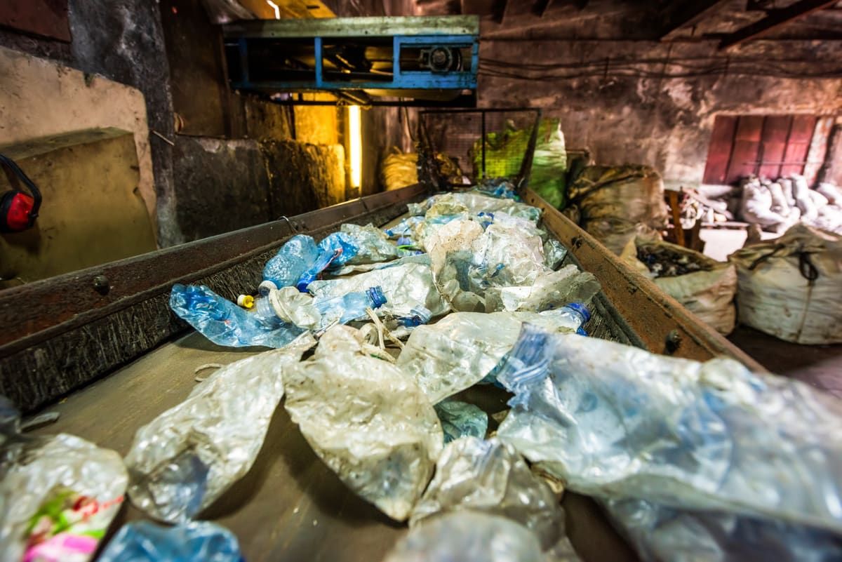 Botellas y film plástico en la cinta de preselección de una planta de reciclaje